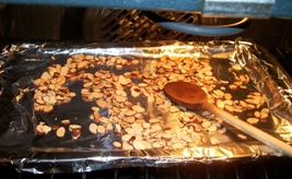 almonds toasting in the oven with spoon